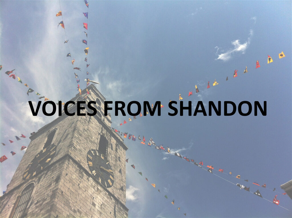 Colour photo tken looking upwards at an old stone church clock tower with blue sky behind. Lines of colourful flags extend from the top of the tower in all directions, blowing upwards in the wind. Black text over the image reads 'Voices From Shandon'.
