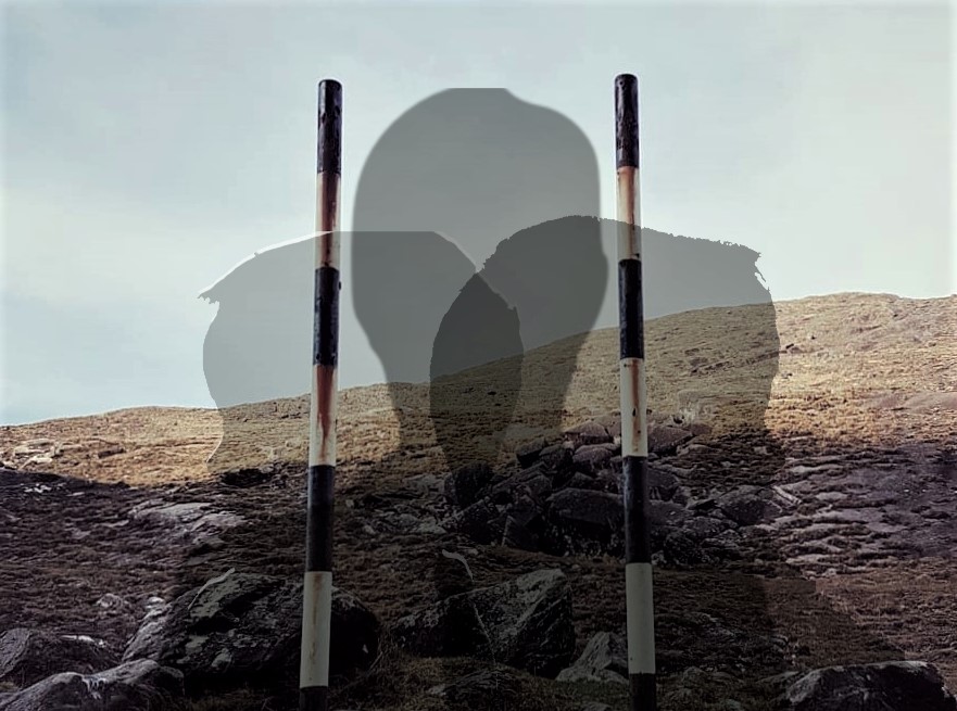 Composite image: the background is a colour photograph of a rocky mountain landscape topped with grey sky. In the center foreground are two old black and white striped signposts about a metre apart: the sign is missing or has been removed. Overlaid on this image are the partly transparent head and shoulder silhouettes of three human figures.